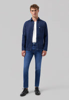 Sustainable MUD Jeans in dark blue denim, crafted from organic cotton, worn with a black ribbed sweater.