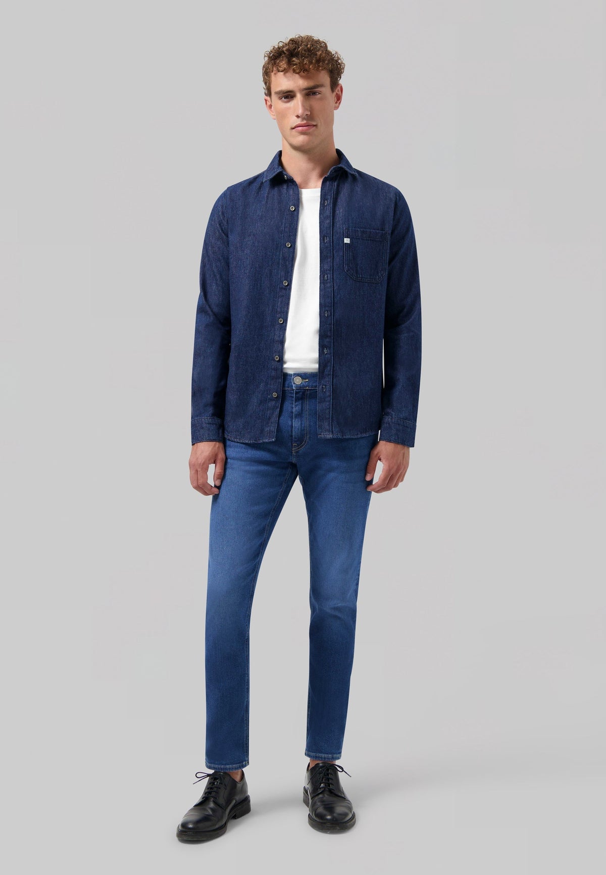 Sustainable MUD Jeans in dark blue denim, crafted from organic cotton, worn with a black ribbed sweater.