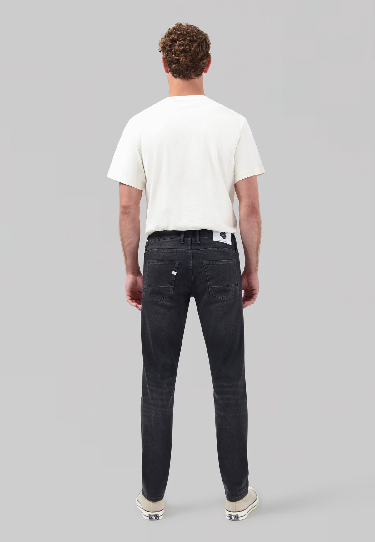 Sustainable MUD Jeans in dark blue denim, crafted from organic cotton with a modern fit, paired with casual sneakers.
