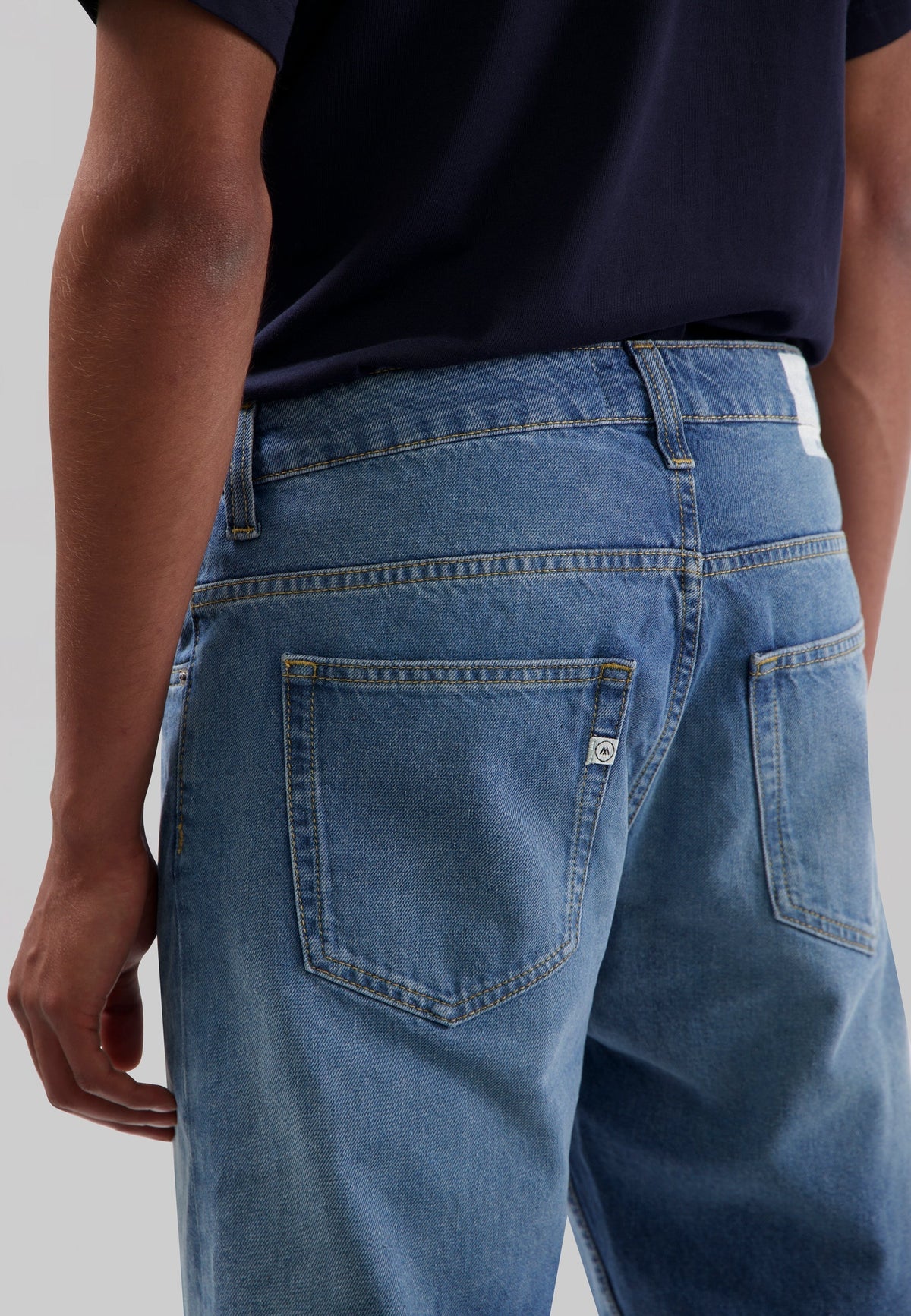 Sustainable dark wash MUD Jeans crafted from organic cotton, featuring a classic fit, styled with white sneakers.
