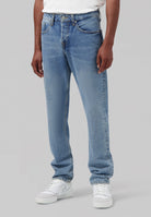 Sustainable MUD Jeans in classic blue denim, featuring ethical design and relaxed fit, paired with a white t-shirt.