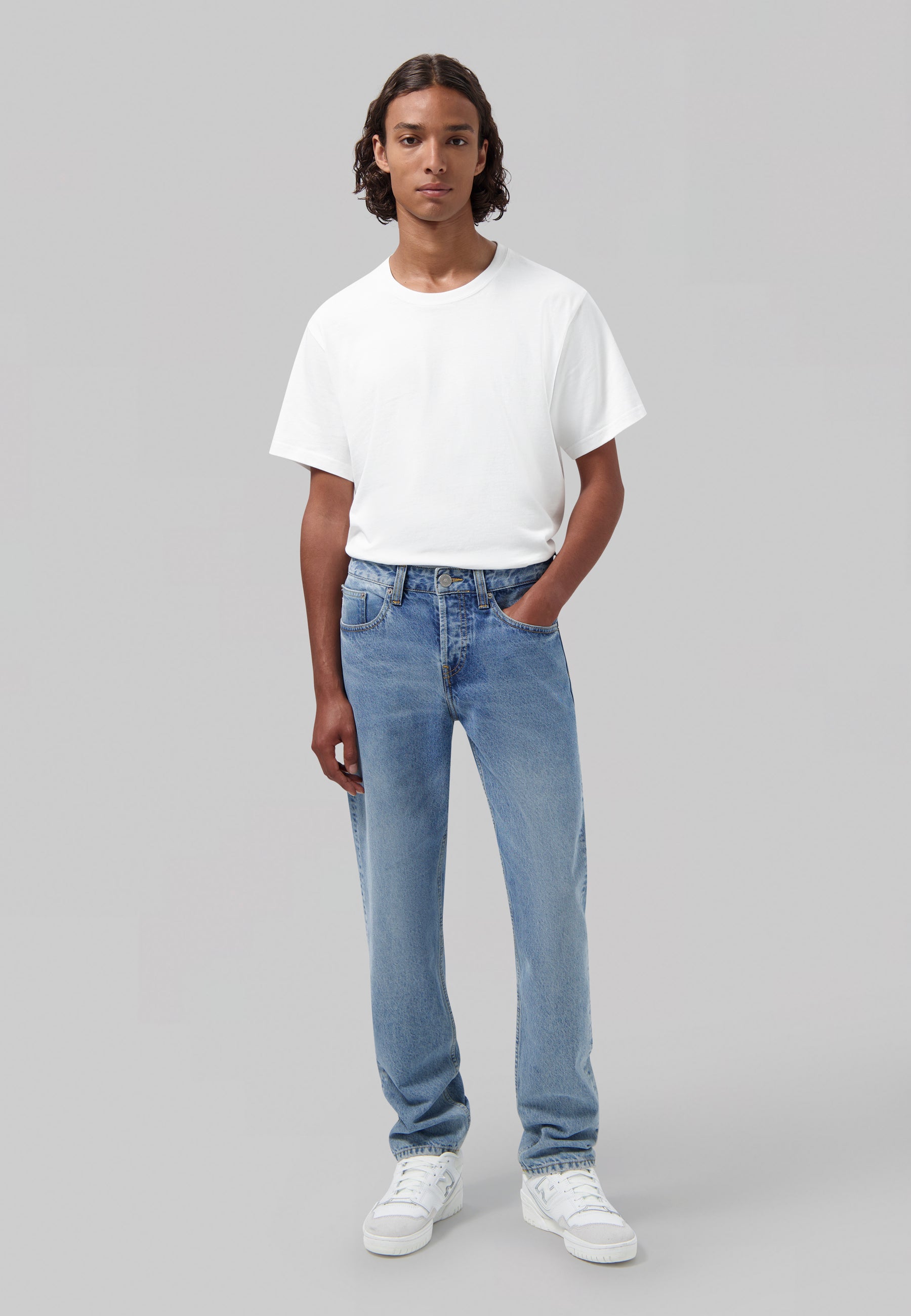 Sustainable MUD Jeans made from organic cotton, classic fit in faded blue denim, paired with white sneakers.