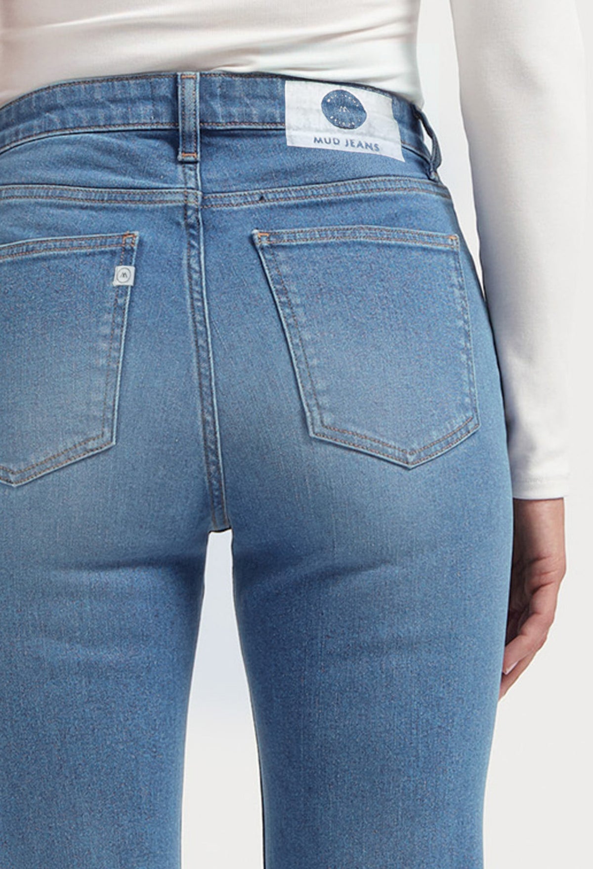 Back view of light blue sustainable MUD Jeans crafted from organic cotton, showcasing classic pocket stitching and white label.