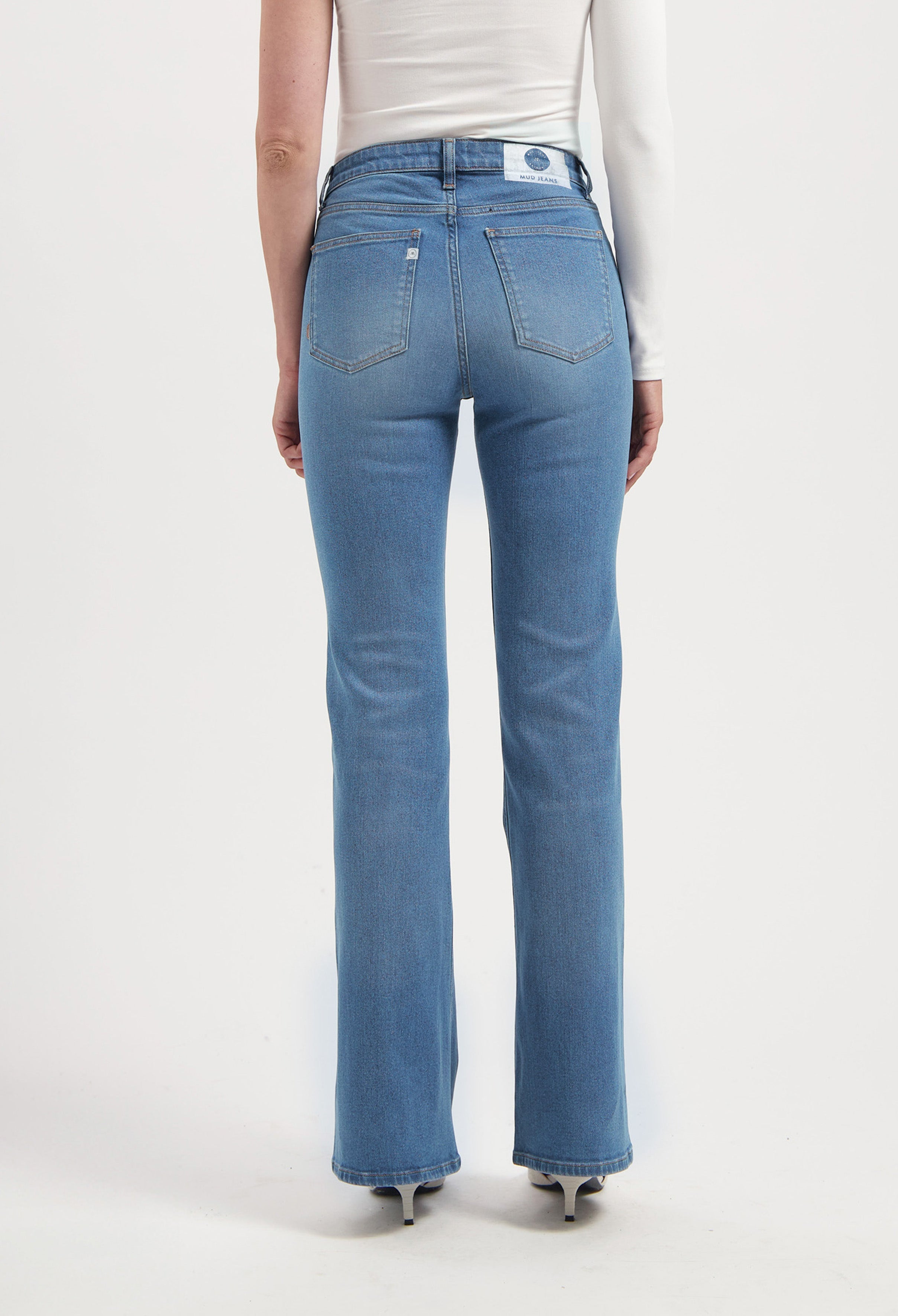 Back view of a person wearing MUD Jeans, sustainable blue denim with a straight-leg fit, paired with a simple white top.
