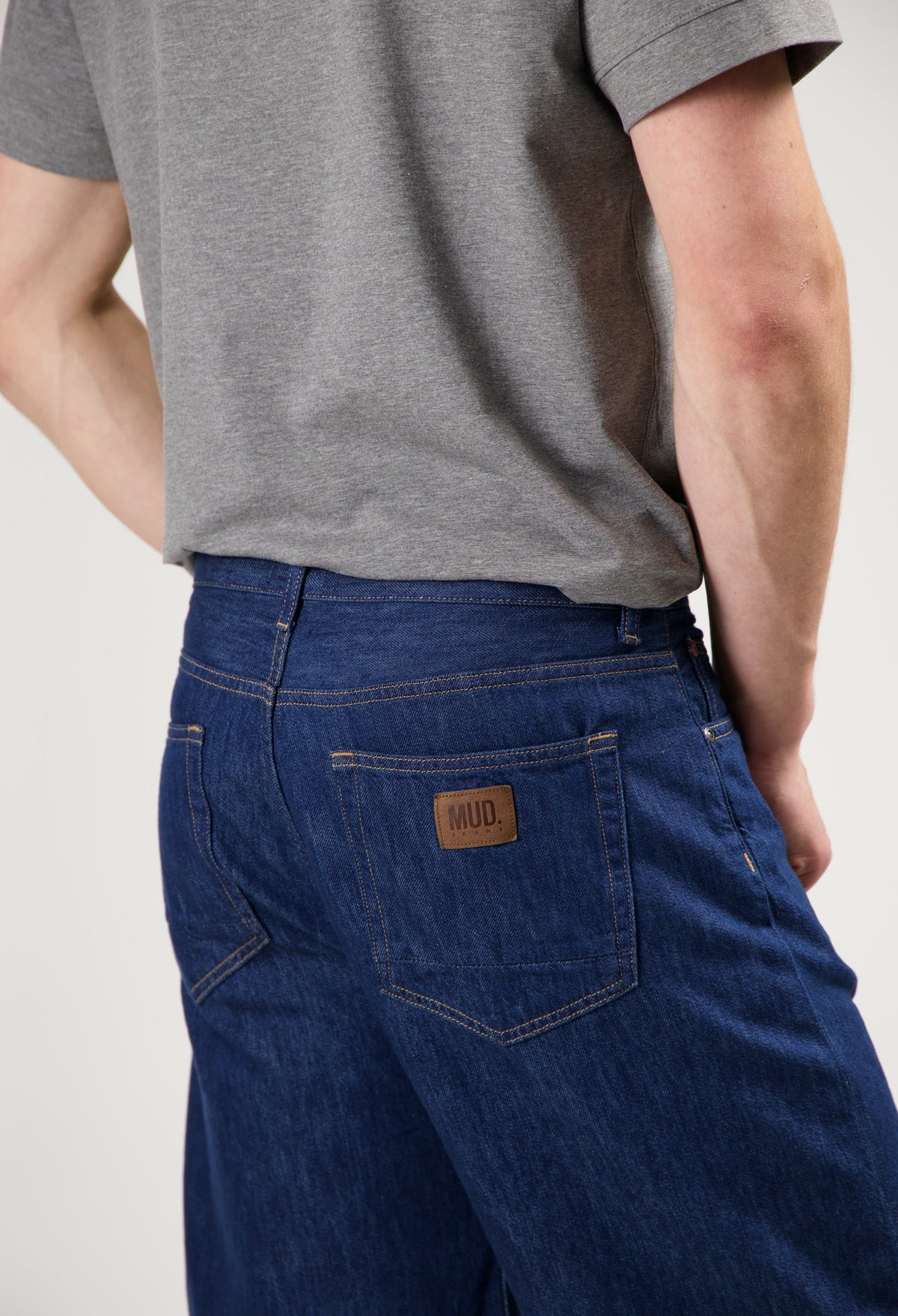 Sustainable MUD Jeans in light blue denim, crafted from ethical materials, paired with a white T-shirt and sneakers.