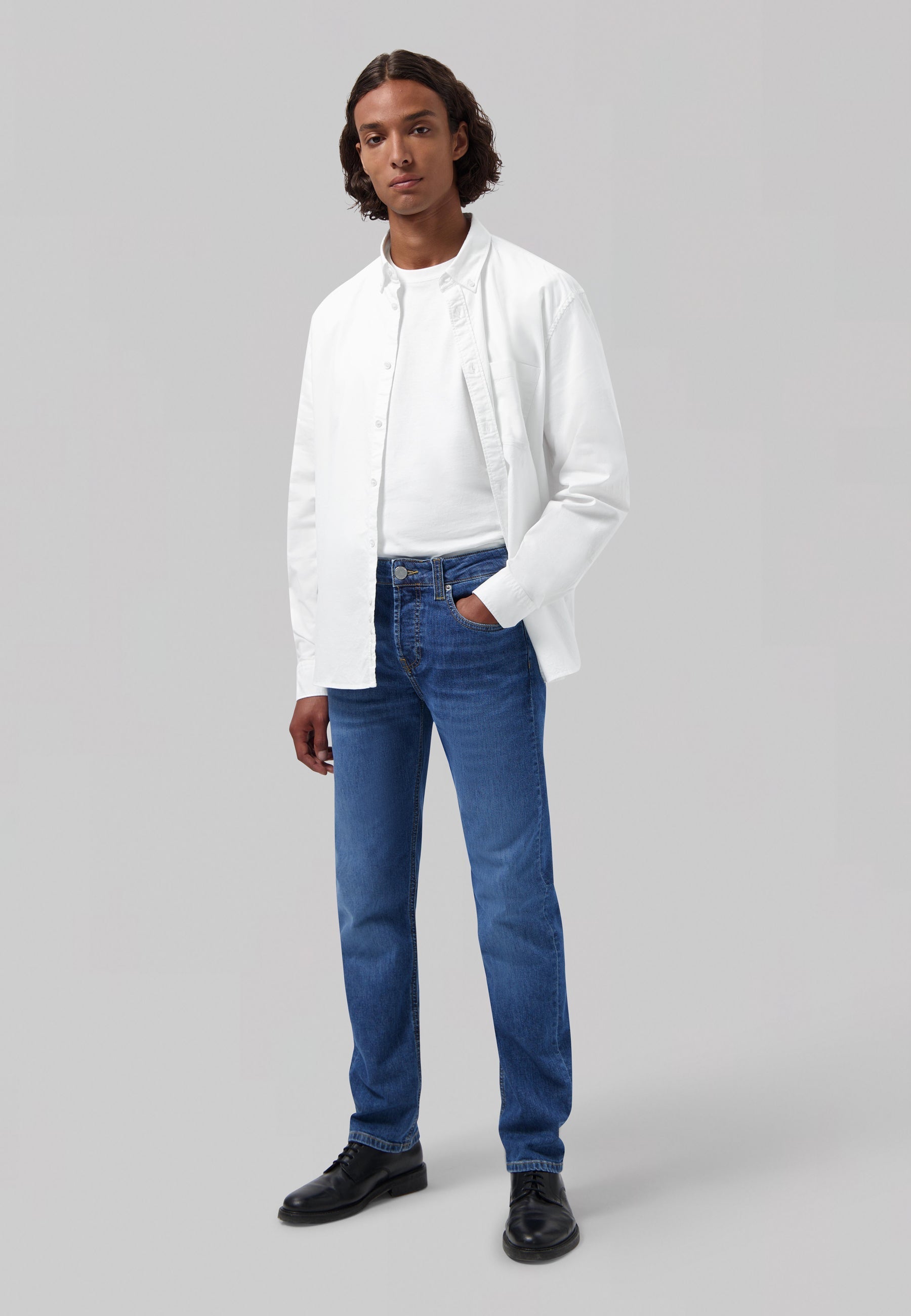 Sustainable MUD Jeans in classic blue denim, paired with a crisp white shirt, showcasing ethical fashion.