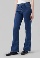Flare blue denim jeans with a high waist, paired with a white top and black pointed flats, showcasing casual style.