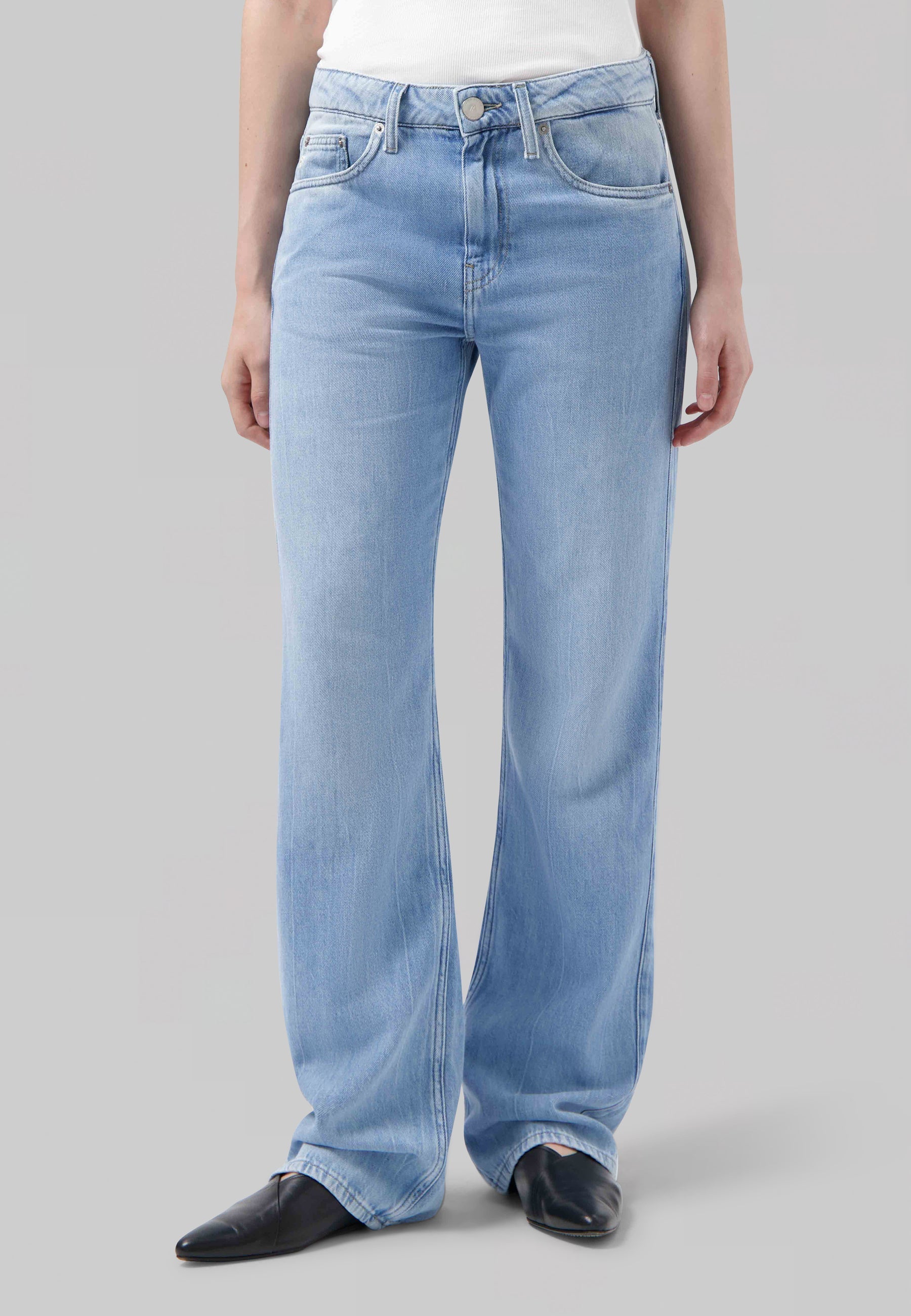 Light blue, high-waisted jeans made from denim, featuring a straight-leg silhouette, styled with a white top and black shoes.