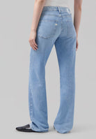 Light blue wide-leg jeans with high waist worn with a sleeveless white top, showcasing back pocket detail and black shoes.