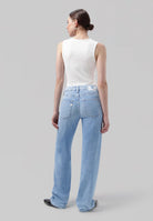Wide-leg light blue jeans in soft denim, paired with a white sleeveless top, creating a casual chic look.