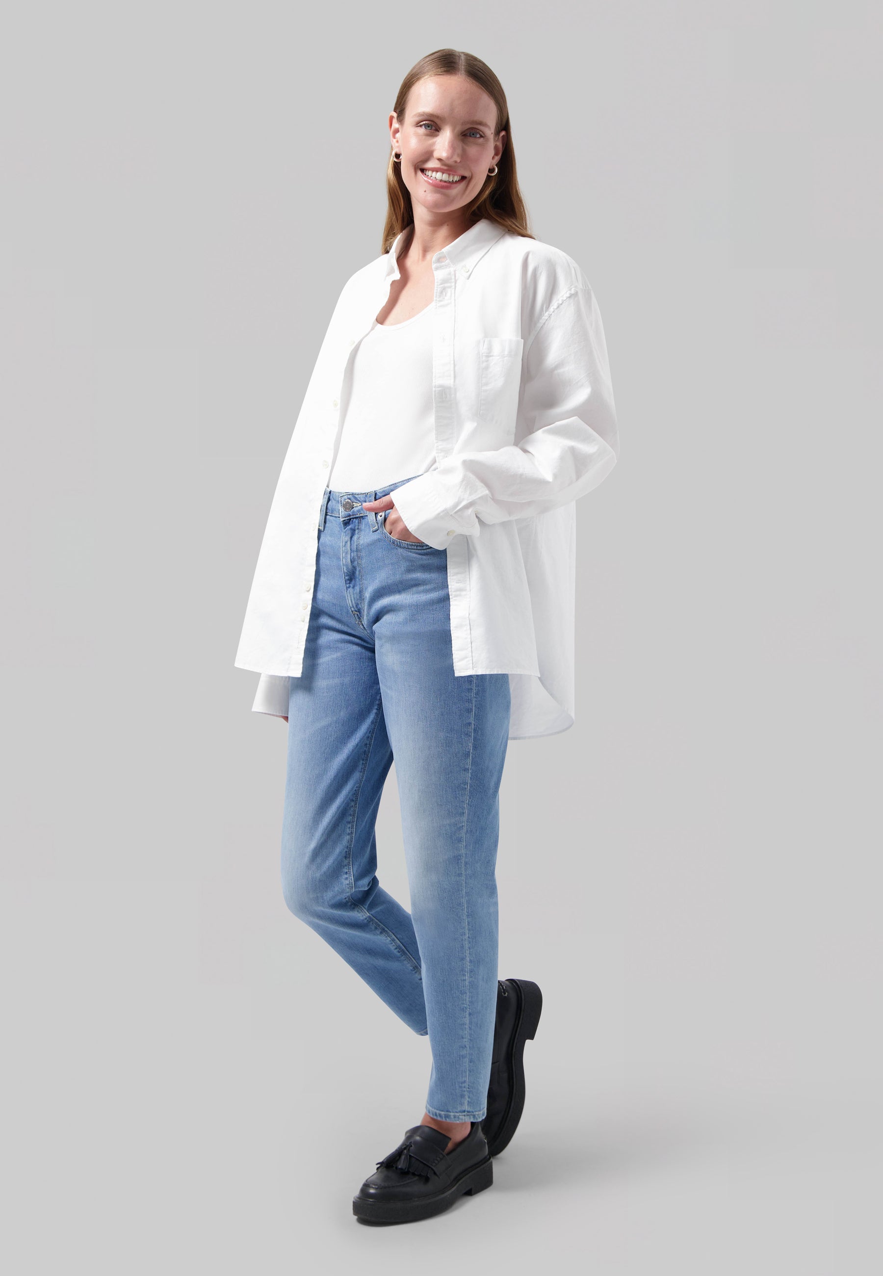 Casual outfit featuring light blue jeans and a white shirt, paired with black loafers, highlighting relaxed fashion style.