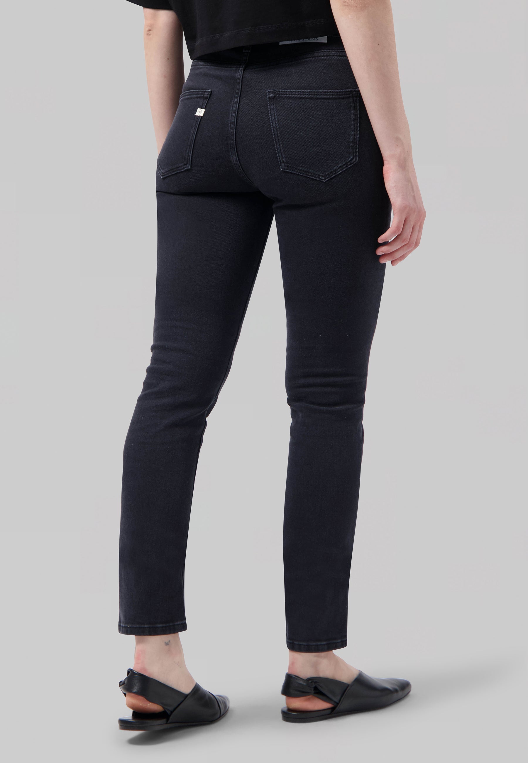 Dark blue, high-waisted skinny jeans with back pockets, worn with black slingback flats and a black crop top.