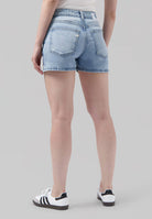 High-waisted light blue denim shorts with back pockets, worn with a simple white top and casual white sneakers.
