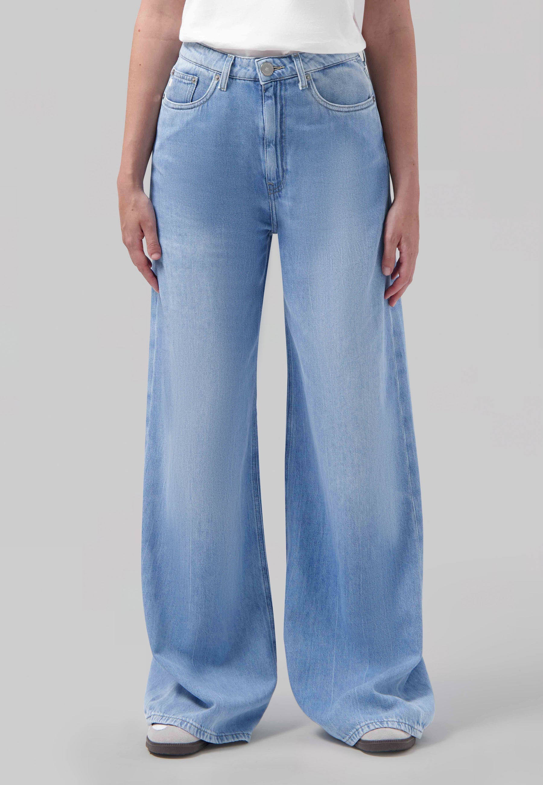 High-waisted wide-leg light blue jeans displayed on model, paired with a plain white top, showcasing casual style fashion.