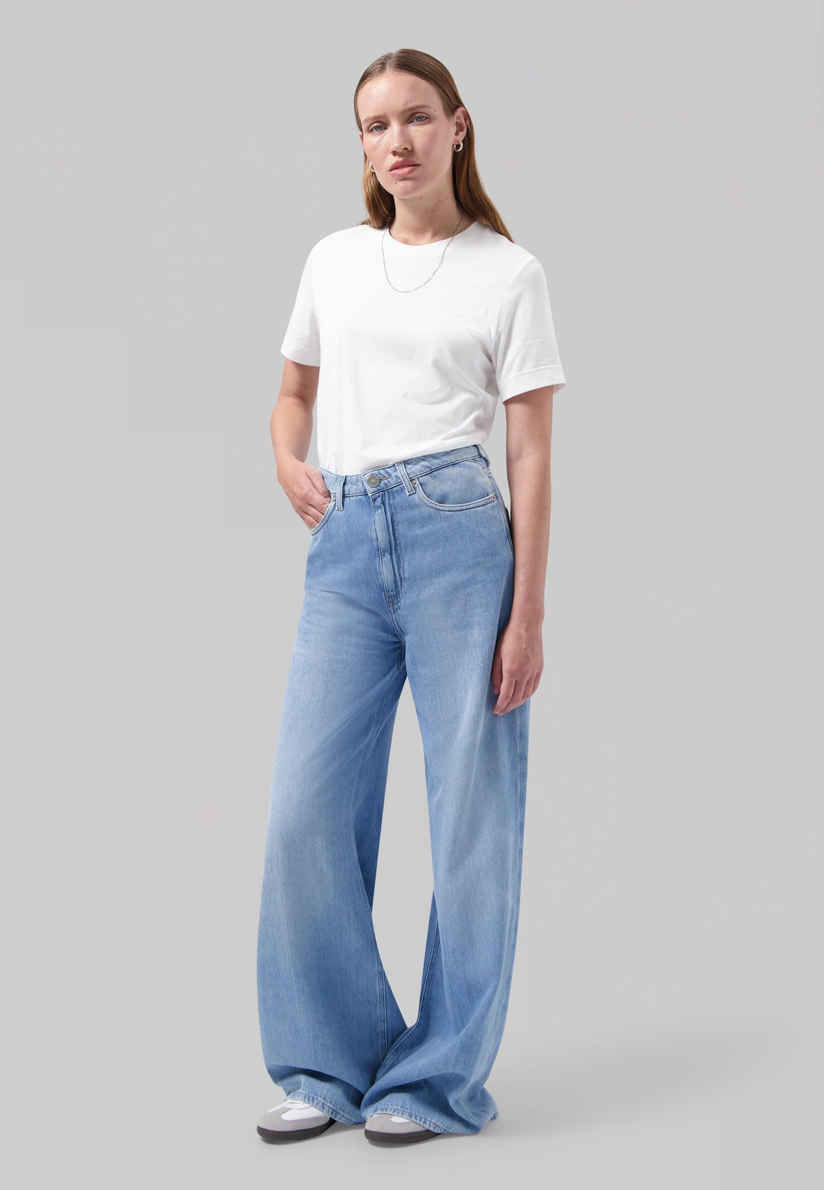 Woman in wide-leg, light blue denim jeans and plain white T-shirt, featuring casual style with relaxed fit jeans.