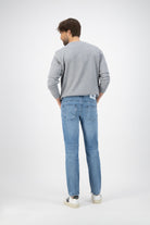 Sustainable MUD Jeans in deep indigo denim, classic straight fit, showcasing ethical fashion choices with casual white sneakers.