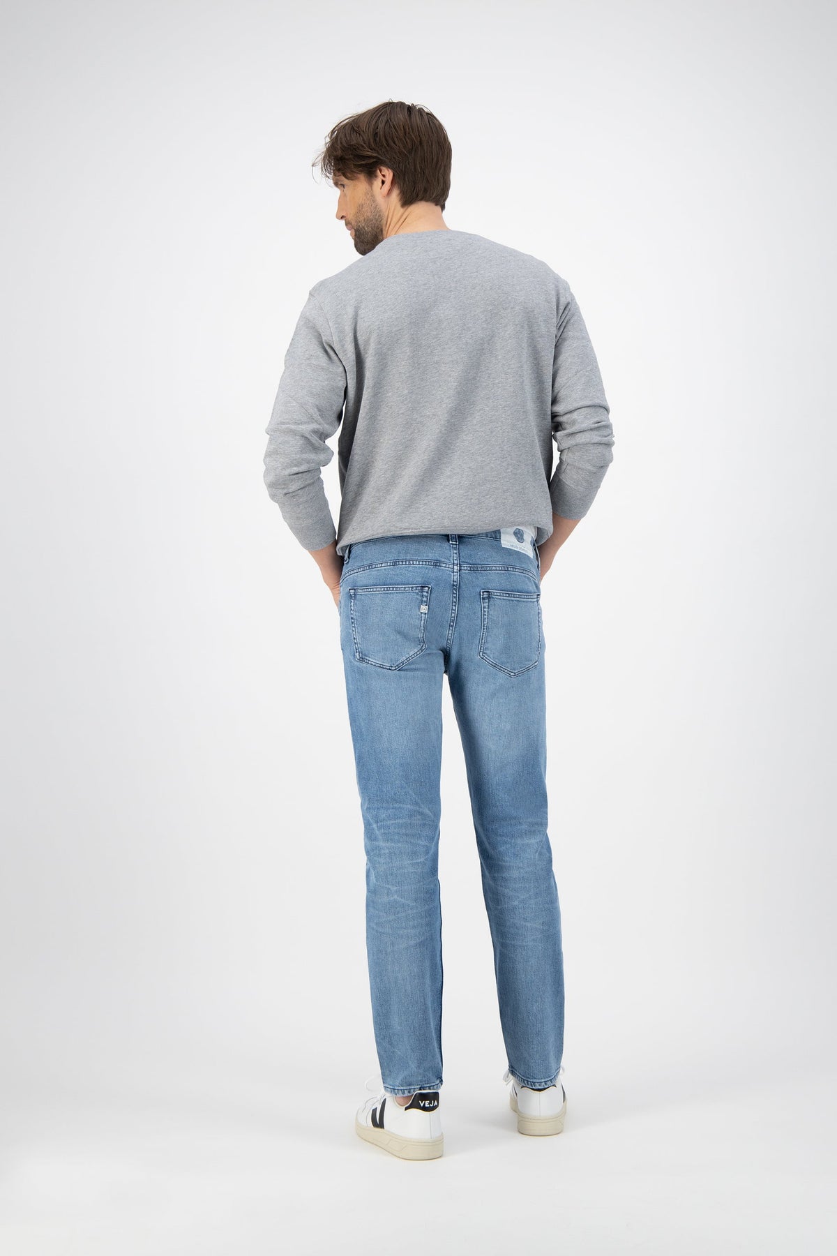 Sustainable MUD Jeans in deep indigo denim, classic straight fit, showcasing ethical fashion choices with casual white sneakers.