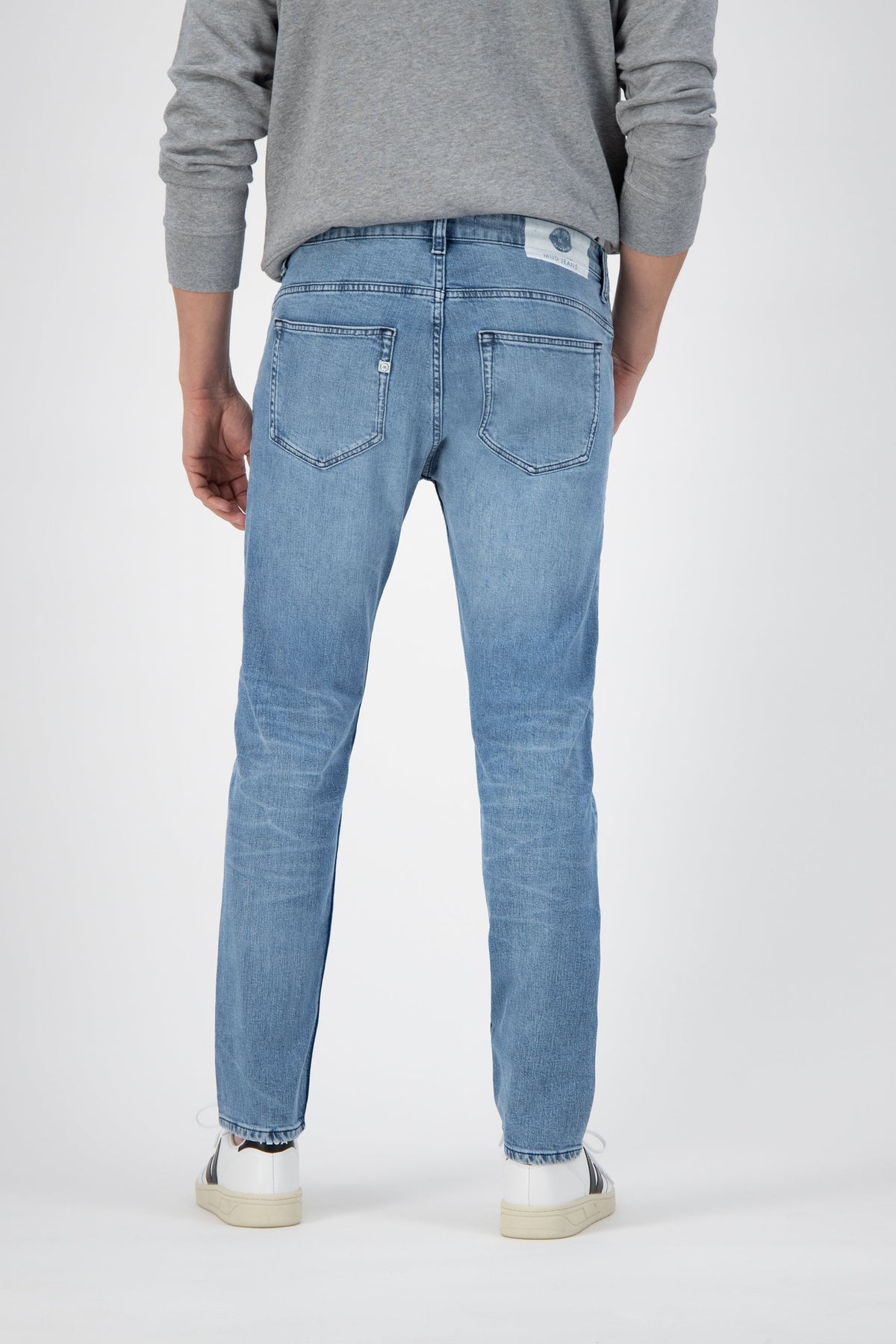 Sustainable MUD Jeans in dark blue denim, paired with a black T-shirt, promoting ethical fashion style.