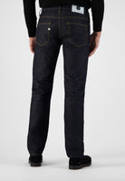 Sustainable MUD Jeans in dark blue denim, crafted ethically, paired with a black high-neck sweater, rear view.