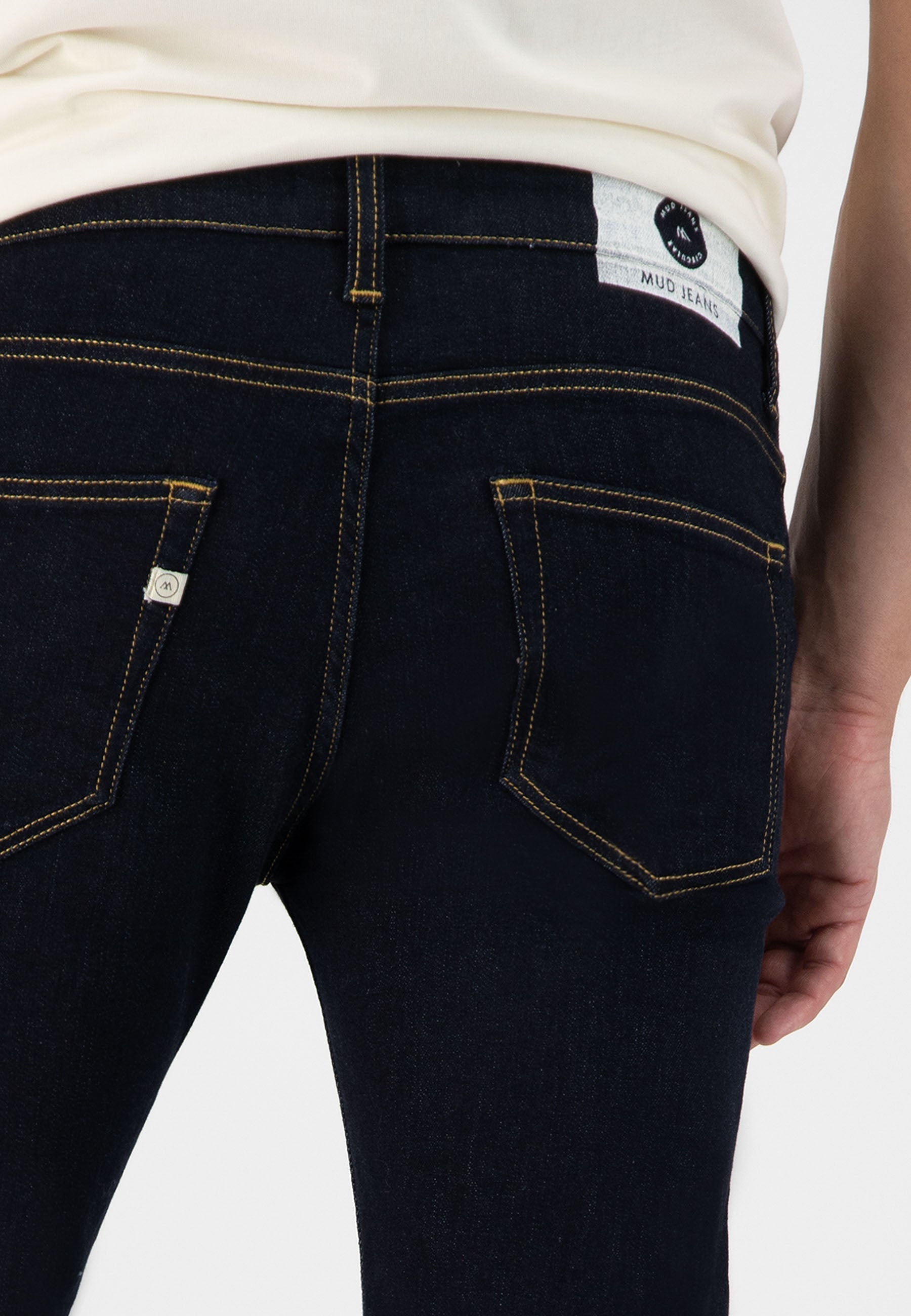 Sustainable MUD Jeans made from organic cotton, showcasing a sleek fit in light blue denim, paired with dark shoes.