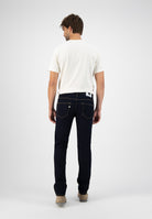 Sustainable MUD Jeans in light blue denim, crafted from organic cotton, worn with a black shirt and brown boots.
