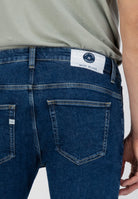 Sustainable MUD Jeans in light blue denim, showcasing ethical fashion with a classic fit, worn with neutral boots.
