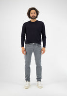Sustainable MUD Jeans crafted from organic cotton, featuring dark blue denim in a slim fit, paired with a black t-shirt.