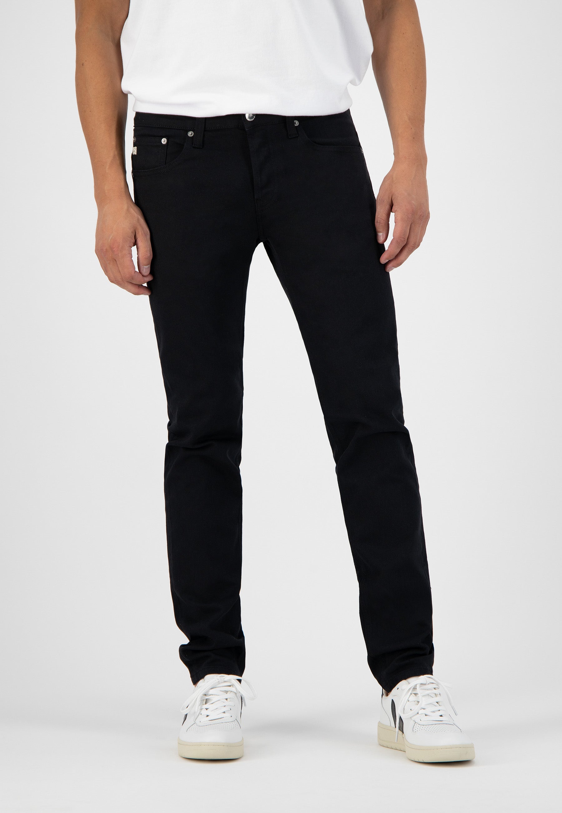 Sustainable MUD Jeans in dark denim, featuring a slim fit design, paired with a classic white tee and sneakers.