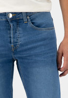 Sustainable MUD Jeans featuring dark blue cargo style, crafted ethically, worn with a black top and sneakers.