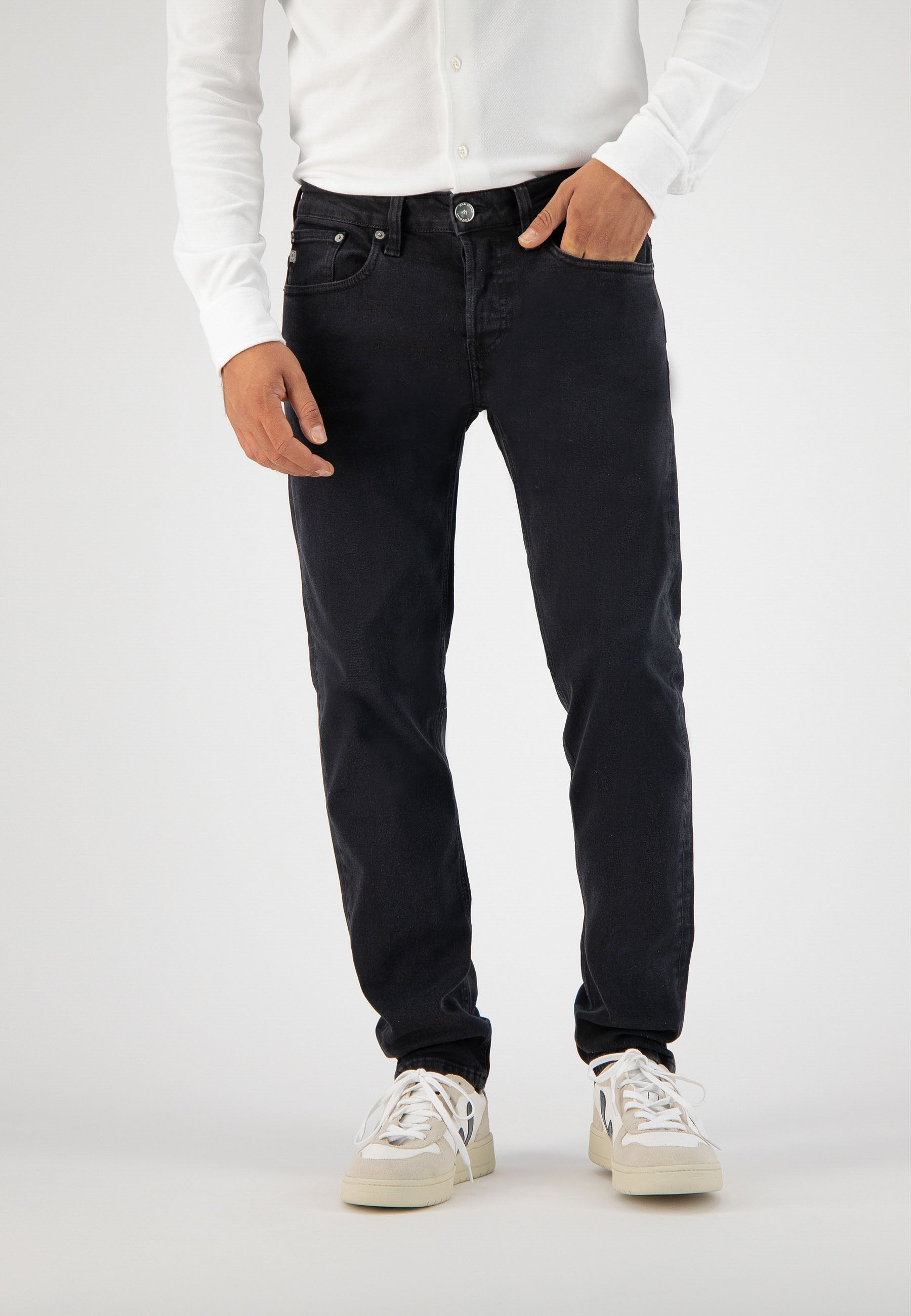 Sustainable MUD Jeans in black denim with a classic fit, paired with a white cardigan, showcasing ethical fashion.