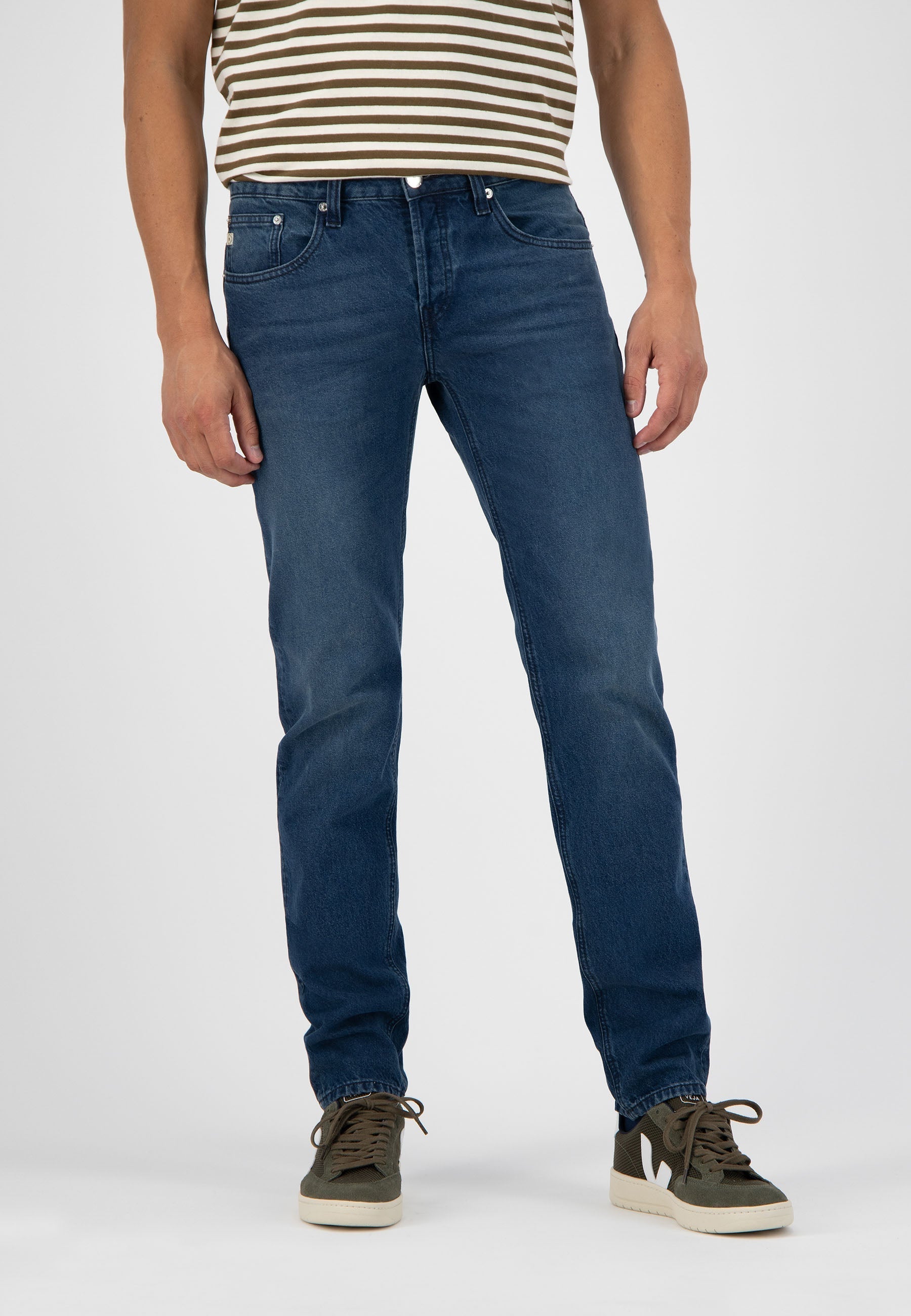 Sustainable MUD Jeans made from eco-friendly denim in deep blue, showcasing a straight-leg fit paired with beige loafers.