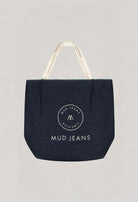 Dark blue denim tote bag from MUD Jeans, featuring cream handles and circular logo, emphasizing sustainable fashion.