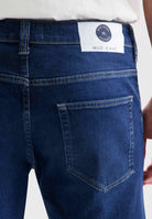 Sustainable MUD Jeans sleeveless jacket in dark blue denim, paired with a matching blue cap, showcasing eco-friendly fashion.