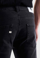 Sustainable MUD Jeans in dark blue denim, showcasing ethical fashion with a modern fit, paired with a black sweater.