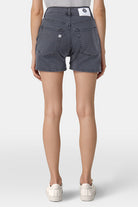 High-waisted, dark gray denim shorts by MUD Jeans with black stitching, shown from the back, paired with white sneakers.