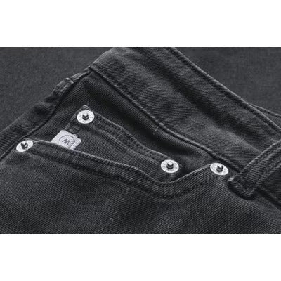 Dark gray denim jeans with metal rivets, showcasing front pocket detail and stitching on a textured fabric surface.