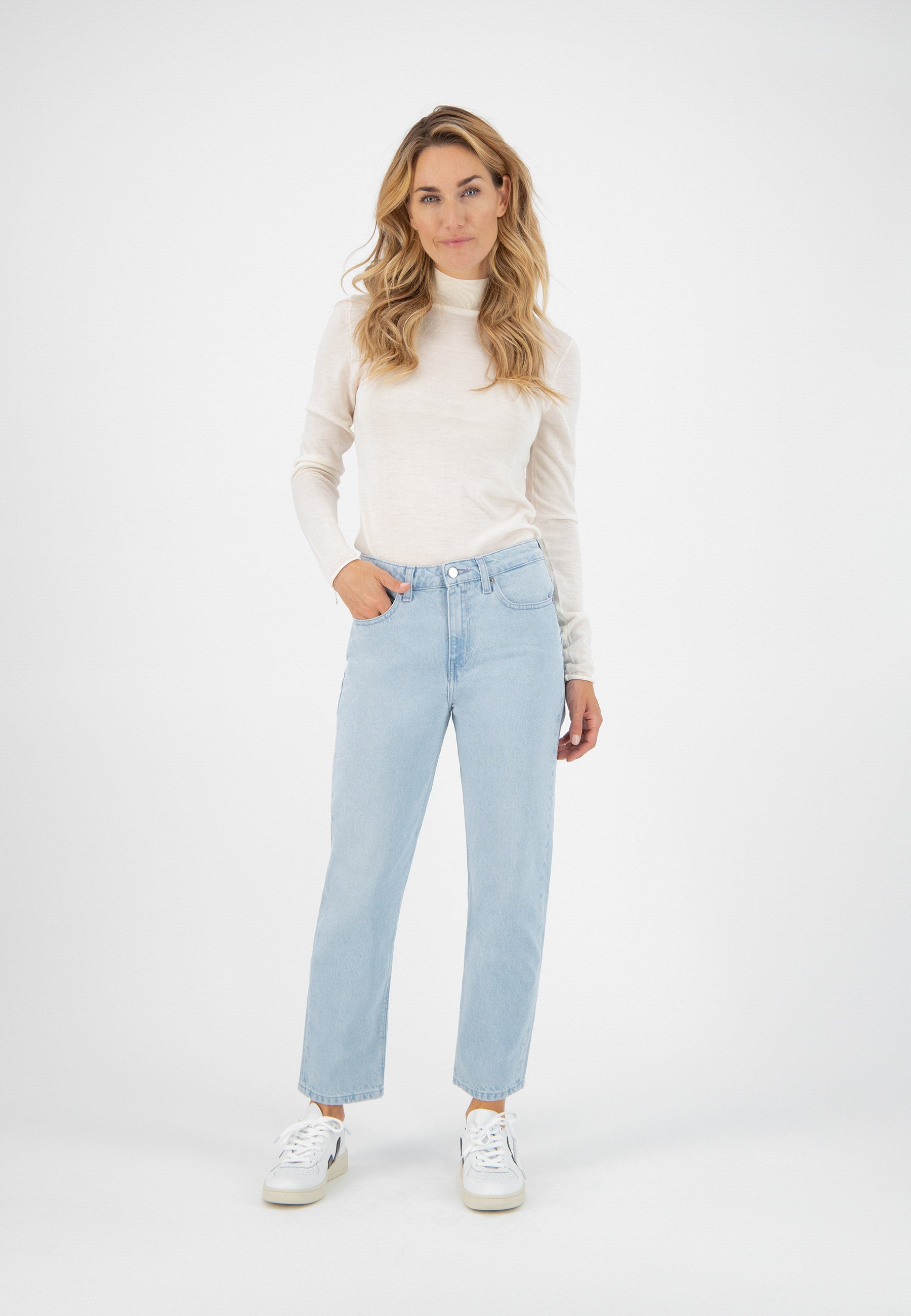 Casual outfit featuring a cream long-sleeve top paired with light blue straight-leg jeans and white sneakers.