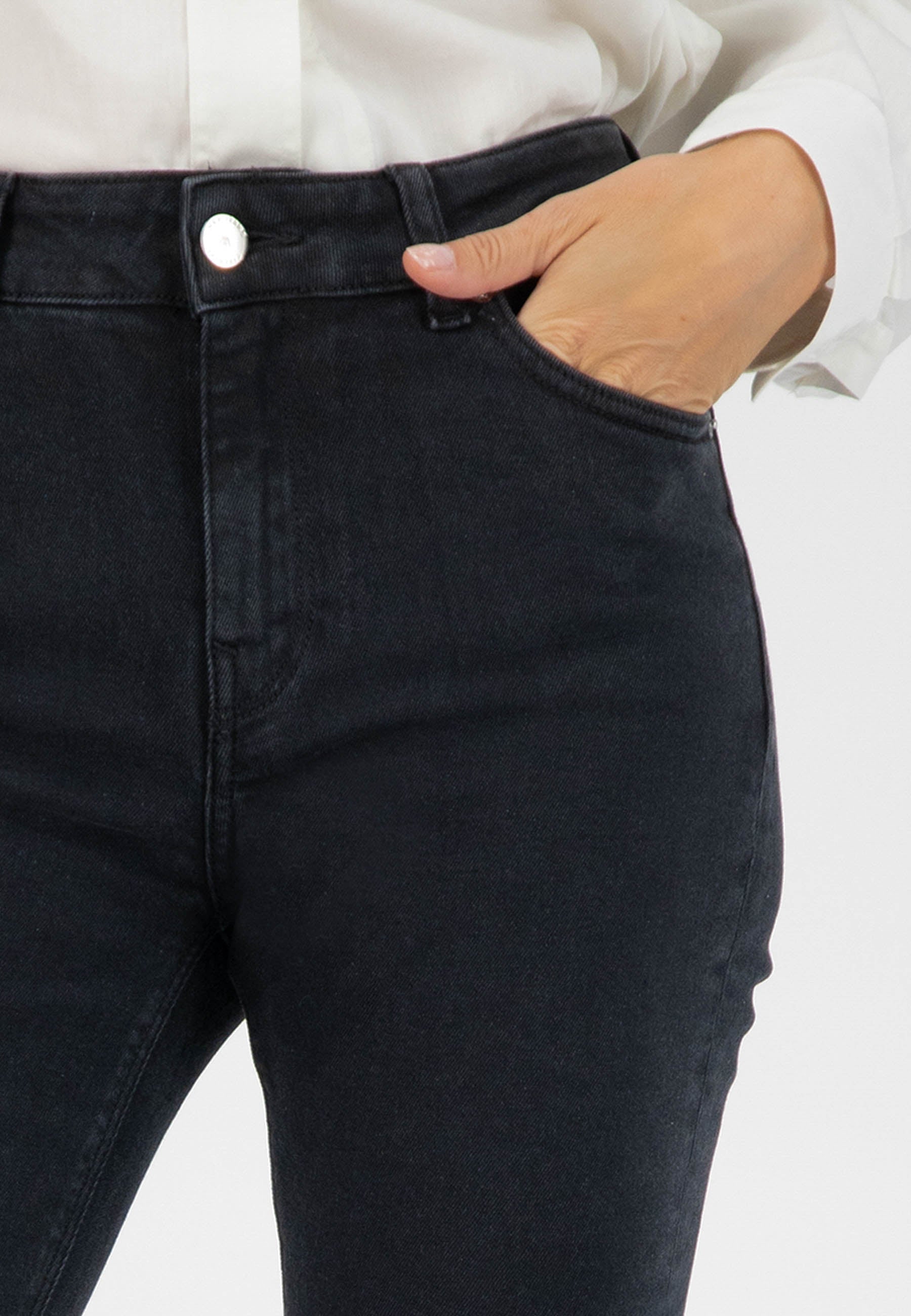 Stylish black denim jeans in a slim-fit design, demonstrated with hand in pocket, paired with a classic white shirt.