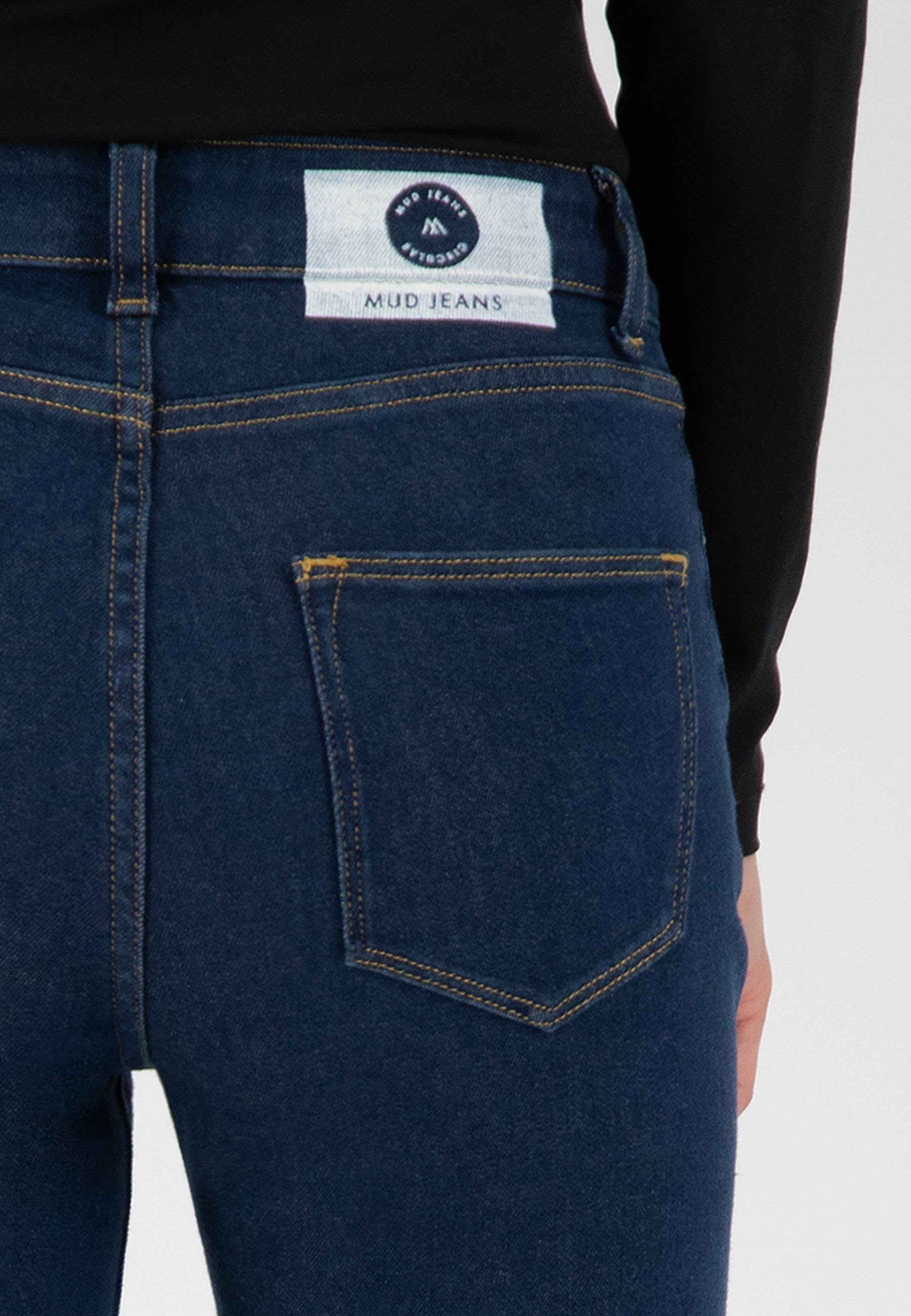 Dark blue MUD Jeans made from organic cotton, showing a back view with a pocket and sustainable label detail.