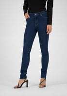 Dark blue skinny jeans paired with a fitted black long-sleeve top and black strappy high heels.
