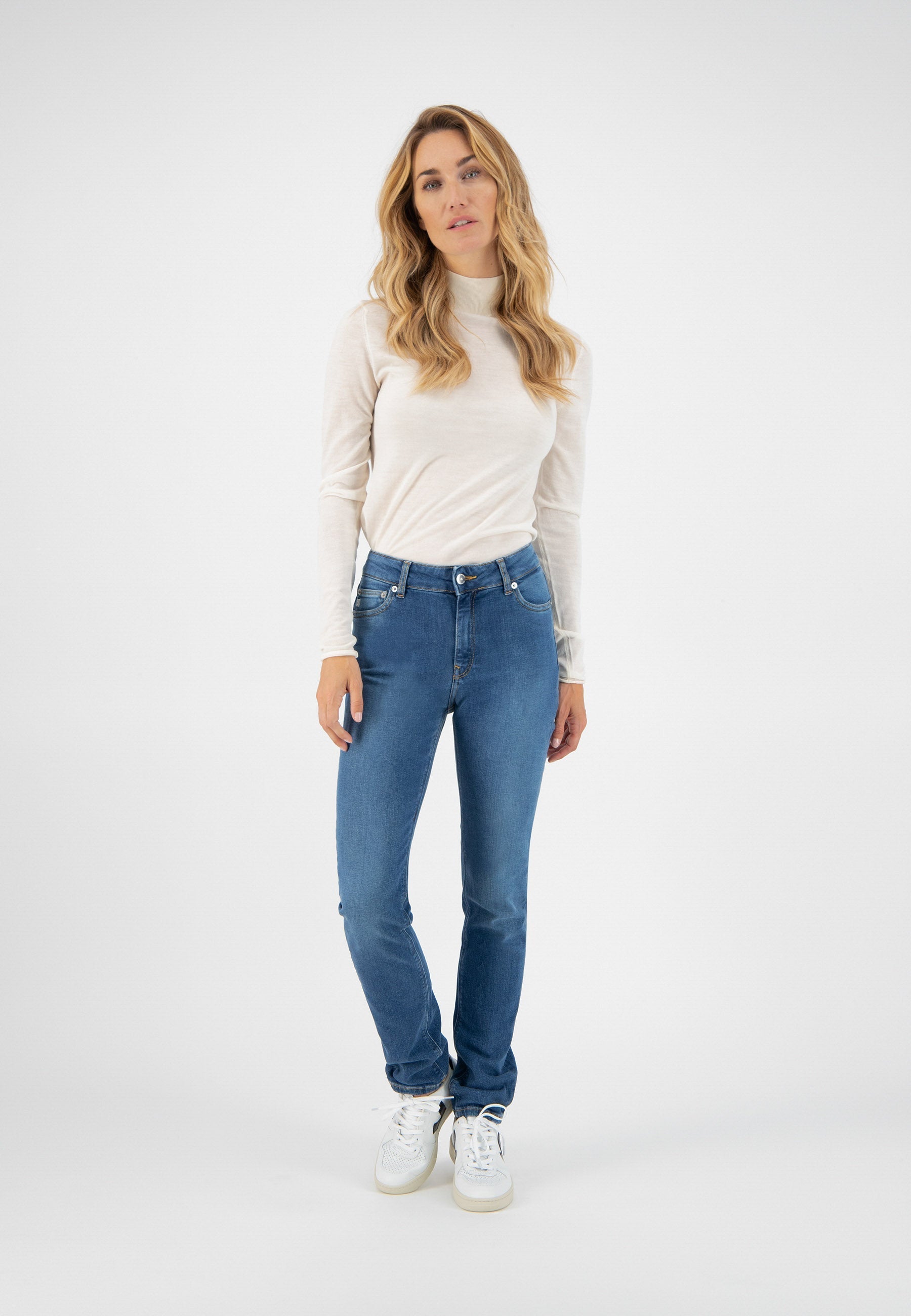 Casual everyday outfit featuring light blue denim jeans paired with a fitted cream turtleneck sweater and white sneakers.