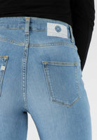 Light blue MUD Jeans made from sustainable materials, featuring a high-waist design with a visible back pocket.