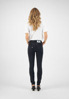 Slim-fit black jeans with a white back patch label, paired with a simple white T-shirt and black high-heeled sandals.
