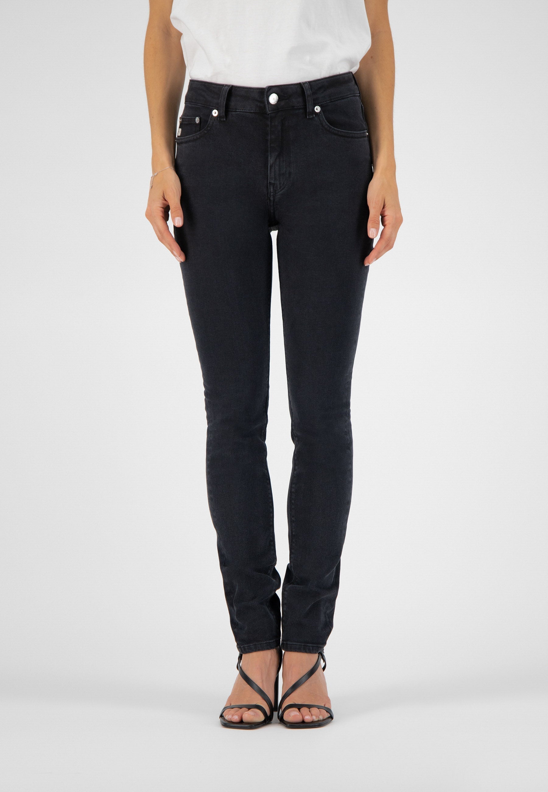 Black slim-fit denim jeans, showcasing high-waisted design, worn with a casual white top and elegant black sandals.