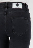 Close-up of sustainable, dark indigo MUD Jeans showing the back pocket detail and fabric label with organic materials.