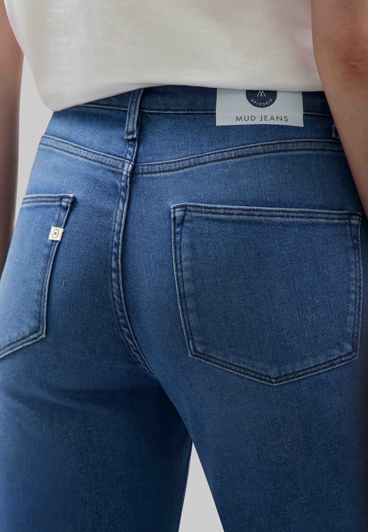 Close-up of sustainable MUD Jeans in dark blue denim, highlighting the slim-fit design worn with a plain white shirt.