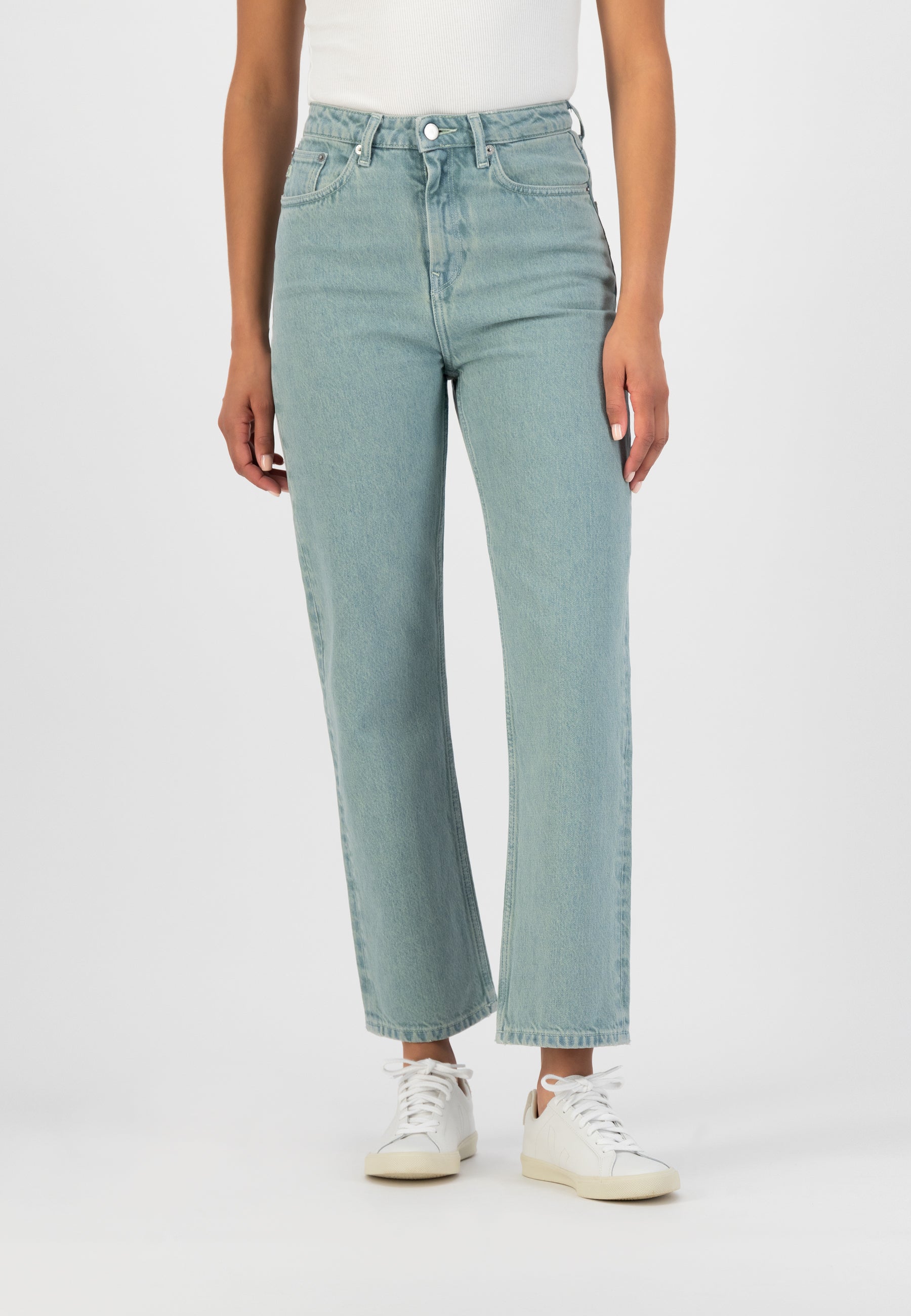 Light blue straight-leg denim jeans paired with a white sleeveless top and casual white sneakers.