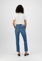 Person wearing mid-blue skinny jeans with back pockets, paired with a white short-sleeve t-shirt, neutral background.