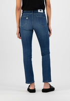Model wearing eco-friendly dark blue straight-leg denim jeans, back view, paired with a black sleeveless top.