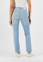 Light blue, high-waisted denim jeans with classic stitching, worn by a person in a white ribbed tank top and white sneakers.